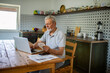 © Marko Geber - Stressed senior man reading bills on kitchen table with laptop