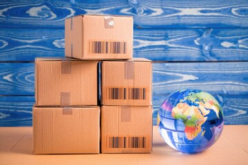 Poster - Stacked cardboard boxes with barcodes and a globe  representing global shipping.