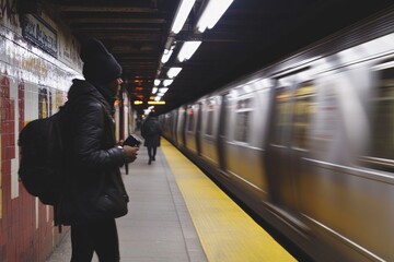 Poster - A person standing at the edge of a subway train platform