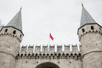 The view of the main gate of the Topkapi Palace with the turkish flag on its top, Istanbul, Turkiye.
