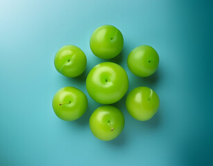 Fruit background. Composition featuring a group of seven plums arranged in a circle on a light blue surface.