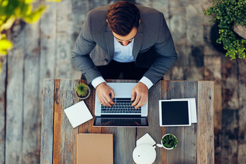 Aufkleber - man is sitting at a desk with a laptop and a tablet. He is typing on the laptop and he is focused on his work. Concept of productivity and concentration