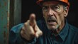 © realone952 - Close-up of an elderly boss in a helmet pointing his finger. Concept of job loss and layoffs at the enterprise