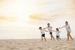 © sorapop - A vibrant scene on the beach with a smiling father happy mother and children playing running and laughing. Quality family time carefree moments and happiness during their summer holiday.
