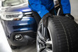 © zphoto83 - A mechanic changes a tire in a modern garage with a blue SUV during daylight hours, showcasing attention to vehicle maintenance
