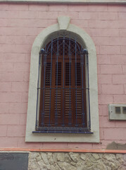 Wall Mural - arched window with wrought iron grille on pink wall