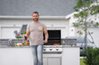 © Volodymyr - Handsome smiling hispanic man making barbecue at backyard. Picnic barbecue party. Chief cook with utensils for barbecue grill. Barbeque on holiday picnic. Man grilling a steak on BBQ.