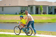 © Volodymyr - Fathers day. Boy learning to ride a bicycle with his father in park on summer day. Father teaching his son cycling on bike. Father learn little son to ride a bicycle. Father support kid. Happy Fathers