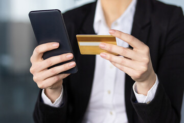 Poster - Businesswoman holds smartphone and credit card, conducting online payment. Professional attire suggests office environment. Illustrates digital transaction, security, convenience in modern business.