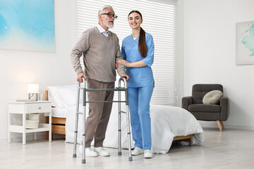 Wall Mural - Nurse helping senior man with walking frame in clinic