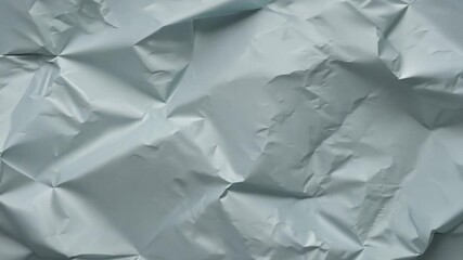 Leinwandbilder - A light blue sheet of paper is crumpled into intricate folds, creating shadows and depth. The overall look is minimalist, highlighting the texture and color.