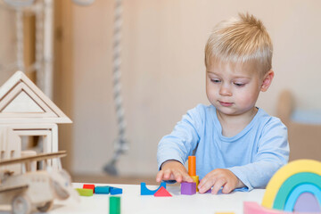 a little boy of 2 years old is playing a developing logistics constructor. children's wooden toys. m