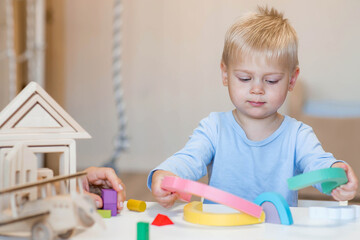 a little boy of 2 years old is playing a developing logistics constructor. children's wooden toys. m
