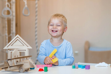 a little boy of 2 years old is playing a developing logistics constructor. children's wooden toys. m