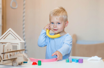 A little boy of 2 years old is playing a developing logistics constructor. Children's wooden toys. Montessori for child development.