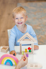 A little boy of 2 years old is playing a developing logistics constructor. Children's wooden toys. Montessori for child development.