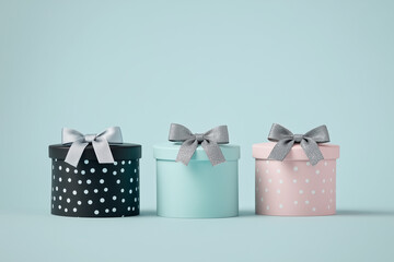 Small gift boxes of different colors and patterns arranged in a row on a white table against a blue background.	
