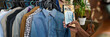 © pressmaster - Banner of secondhand denim shirt hanging in front of row of casual attire on rack while young female consumer taking picture of apparel