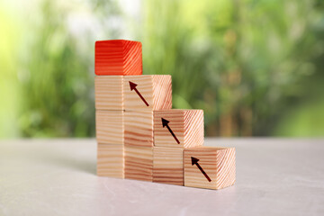 Stair made of wooden blocks on table. Cubes with arrows showing way to red one. Steps to success concept