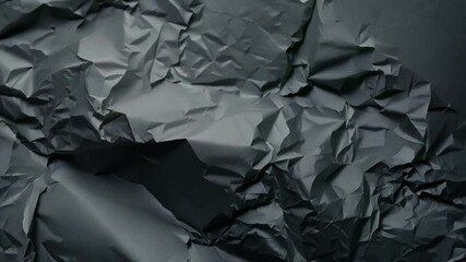 Fototapete - The surface showcases an intricate pattern of crumpled black paper, highlighting depth and texture under soft lighting. This background adds a dramatic element.