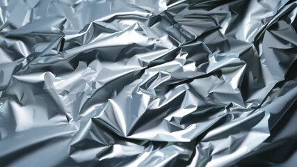 Poster - The close-up displays a crumpled silver foil surface, highlighting intricate folds and creases that catch light and create dynamic reflections.
