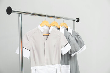 Maids' uniforms on clothing rack against grey background