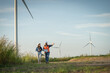 © Thanadon88 - two engineers are walking on a path near a wind farm. One of them is pointing to a wind turbine