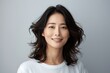 © k - Portrait of a smiling middle-aged Asian woman in a white t-shirt with wavy hair