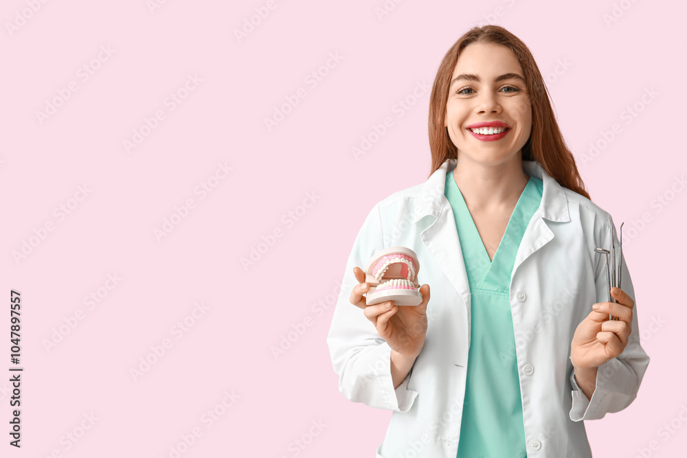 Female dentist with jaw model and dental tools on pink background. World Dentist Day