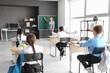 © Pixel-Shot - Mature teacher near chalkboard conducting lesson to little pupils in classroom