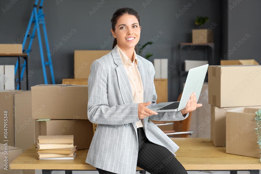 Beautiful businesswoman using laptop in office on moving day