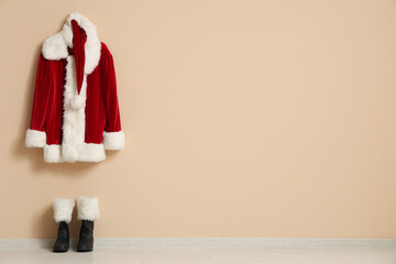 Canvas Print - Hanger with Santa Claus costume and boots near beige wall in room