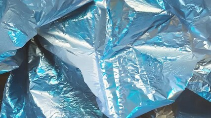 Leinwandbilder - Crumpled blue foil creates a dynamic texture, reflecting light and shadows beautifully against a contrasting dark backdrop, highlighting artistic potential.