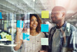 © peopleimages.com - Business people, writing or vision with glass board for agenda, schedule planning or brainstorming at office. Young, group or employees with sticky note for meeting, reminder or project at workplace