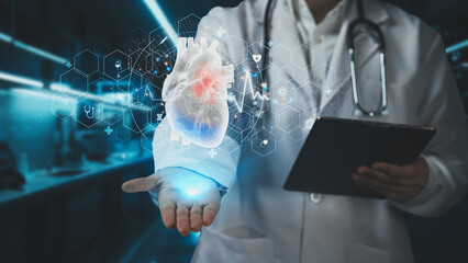 Close up of smart doctor holding tablet and holding heart hologram. Skilled medical worker with lab coat checking and diagnosis heart symptom while preparing for heart surgery. Cardiology. Remedial.