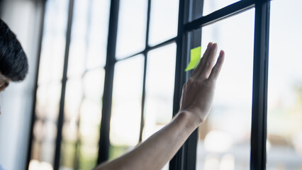 Man organizing project tasks Colorful sticky notes on glass of meeting room