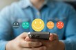 © Thapana_Studio - Customer satisfaction survey via online application, customers use smartphones to express their feedback with emoticons ranging from happy to sad, providing the best service and product quality.