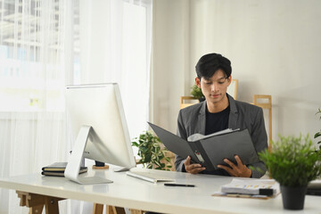 Young entrepreneur reviewing charts and making plans at his office