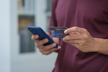 Wall Mural - Close-up of a man's hand holding a bank credit card, highlighting online services for lending and access to credit,demonstrating financial convenience and flexibility for secure digital transactions