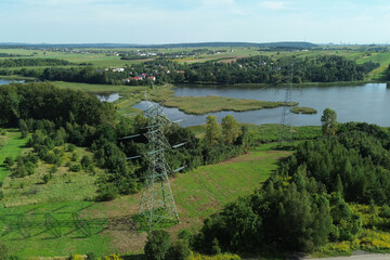 electricity tower crossing lake surrounded by nature