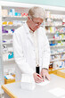 © peopleimages.com - Pharmacist, writing notes and senior man with parcel, medicine and healthcare with prescription. Employee, pharmacy and consultant with package, medical and professional with drug store and checklist