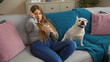 © Krakenimages.com - A beautiful, blonde, young woman relaxes with a cup of coffee beside her happy canine pet in a cozy living room.