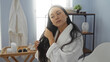 © Krakenimages.com - Beautiful young chinese woman in a spa room, wearing a white robe, combing her long hair, surrounded by a serene and tranquil beauty center interior.