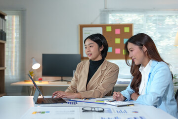 Two Asian businesswomen rejoicing over business success, smiling and expressing joy. Success in starting an online business partner teamwork concept.