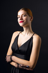 A young redhear girl with clean skin wearing black gloves. Beauty portrait of a woman on a black background in the studio.