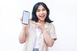 © M Alfan Setyawan - excited asian woman do presenting gesture with pointing finger to smartphone white screen wearing brown casual clothes isolated on white background