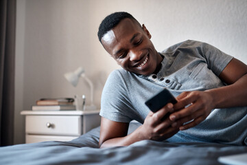 Happy, morning and black man on bed with phone for social media, online chatting and internet in bedroom. Relax, rest and person on smartphone for website, networking and message on weekend in home