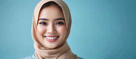 Poster - Portrait of a beautiful young Asian Muslim woman smiling in her headscarf Pearl From The East Joyful Muslim woman in hijab Contemporary fashionable and cheerful Muslim woman with a headscarf