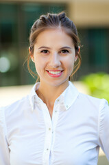 Wall Mural - Young businesswoman smiling outdoors near office building