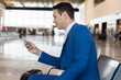 © Minerva Studio - Businessman checking phone at airport